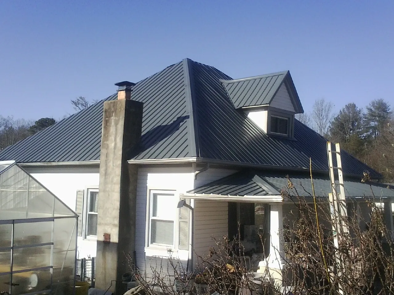 Dark blue standing seam metal roof on a white farmhouse with dormer — Slate & Tile Roof Repair by Roofing Brothers in Benton Harbor