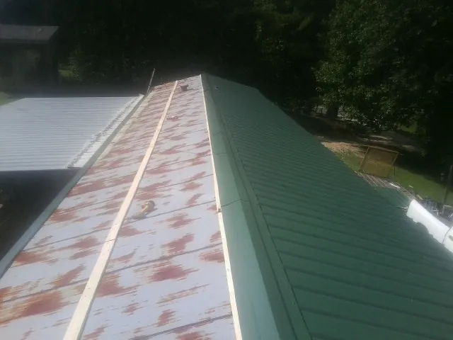 Old rusted panels beside newly installed green metal roofing — Wind Damage Roof Repair by Roofing Brothers in Benton Harbor