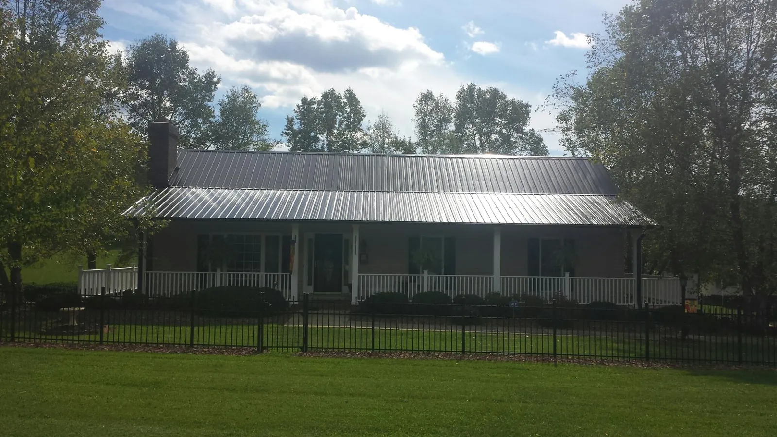 Gray metal roof on a brick ranch with a full width front porch — Gutter Guard Installation work by our crew in Benton Harbor