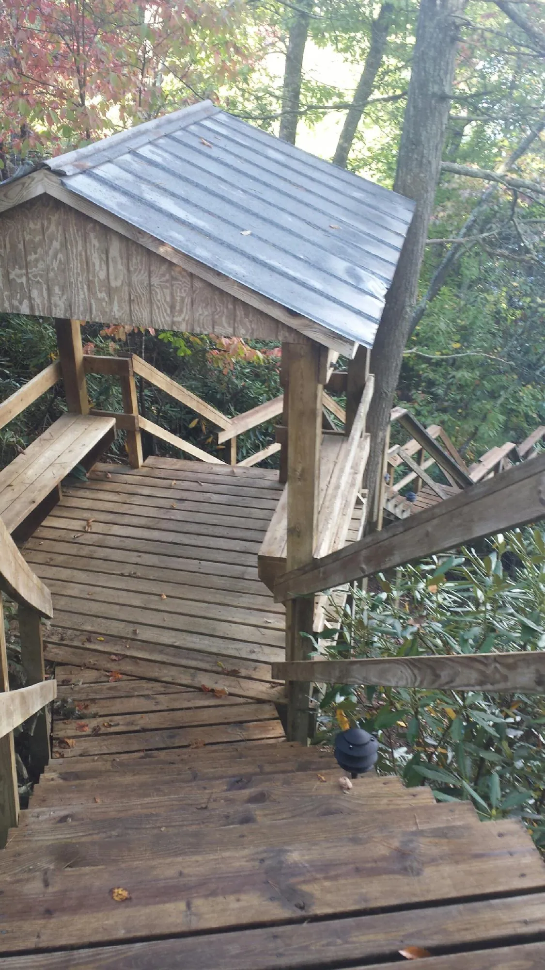 Metal roofed shelter over wooden steps on a wooded walkway — Skylight Repair & Installation work by our crew in Benton Harbor