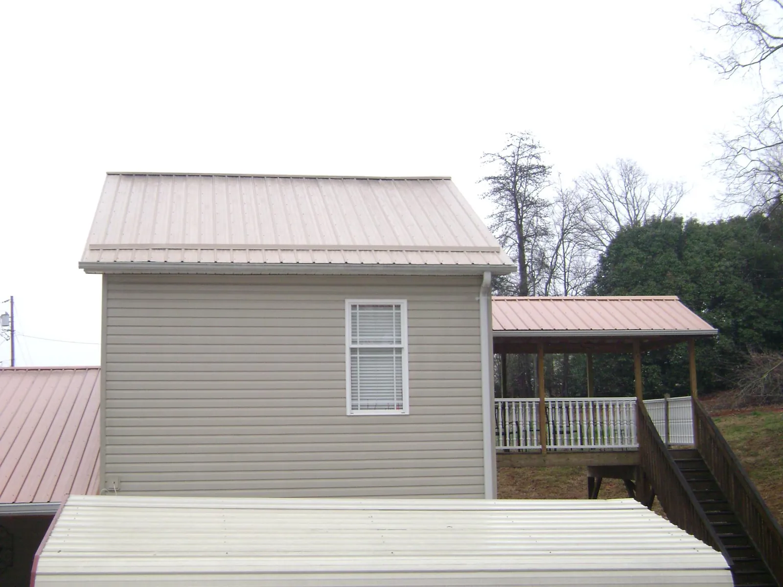 Tan metal roofs on a two story addition and attached porch, from a Roof Replacement job in Benton Harbor